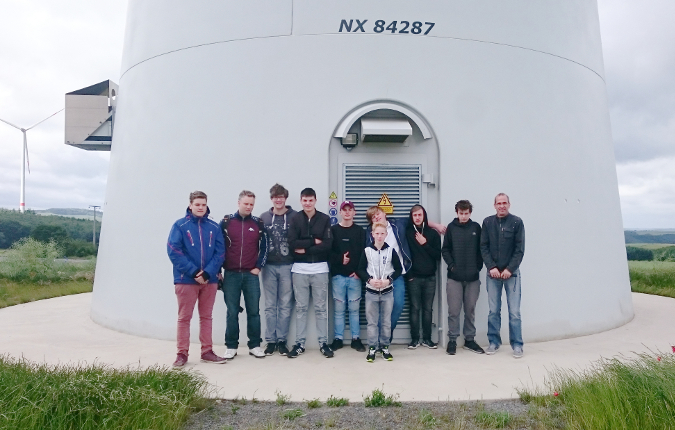 Acht Schüler der Bernardshof-Schule mit den Lehrern vor der Windenergieanlage